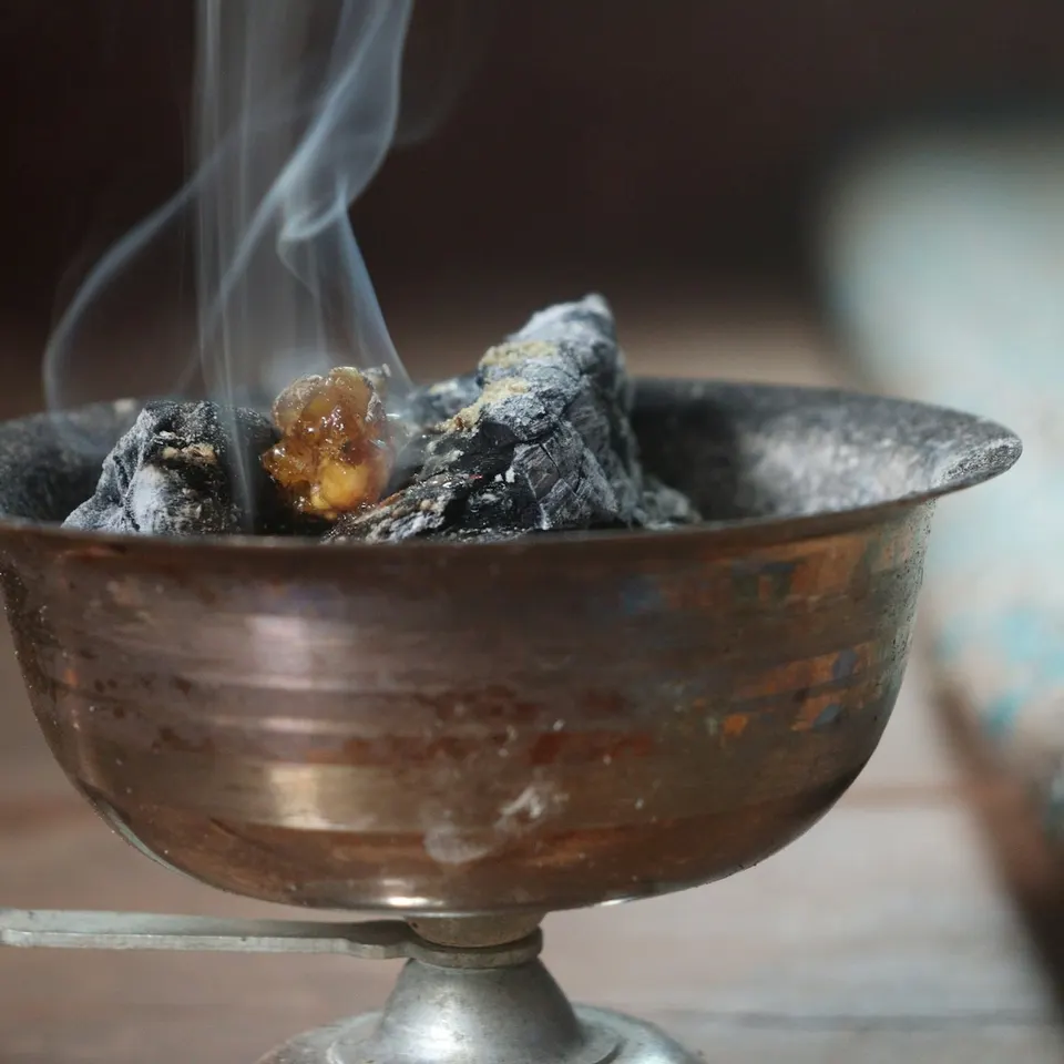 Resin smouldering in a metal burner, with smoke rising